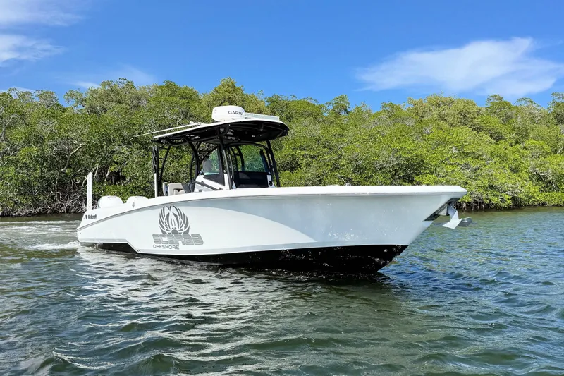 Slide: The Image of 2021 Wellcraft 302 Fisherman boat cruising on water near lush greenery. - 4