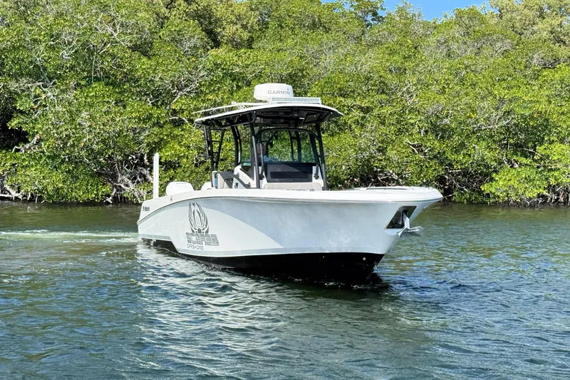 Slide: The Image of 2021 Wellcraft 302 Fisherman boat cruising on a scenic waterway with lush greenery. - 5