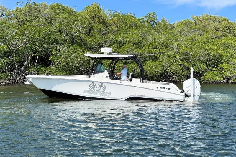 Slide: The Image of 2021 Wellcraft 302 Fisherman boat cruising on a scenic waterway with lush greenery. - 7