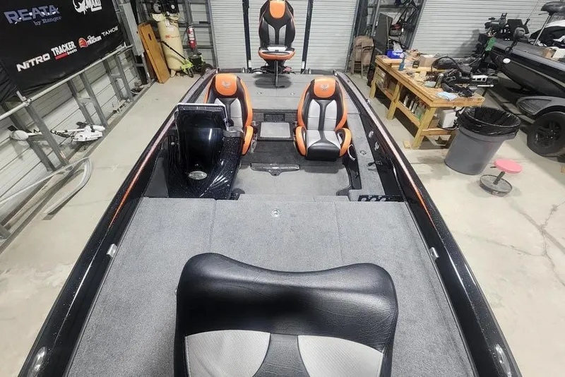 Slide: The Image of 2019 Phoenix 920 ProXP boat interior with orange and black seating in a garage. - 7