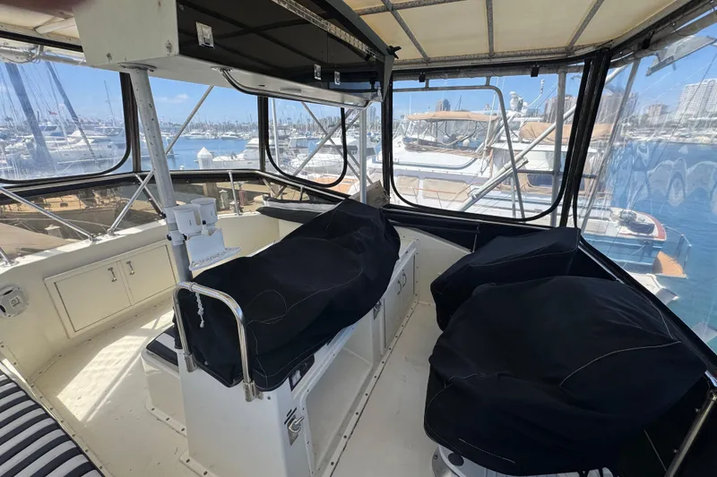 Slide: The Image of Interior view of 1985 Hatteras 45 Convertible yacht cockpit with covered seats and marina backdrop. - 11