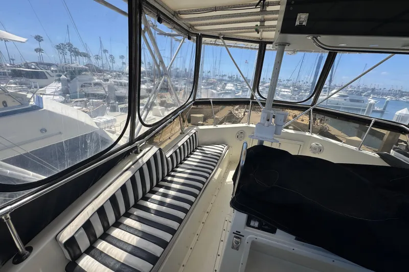 Slide: The Image of Interior view of 1985 Hatteras 45 Convertible yacht with striped seating and marina backdrop. - 12