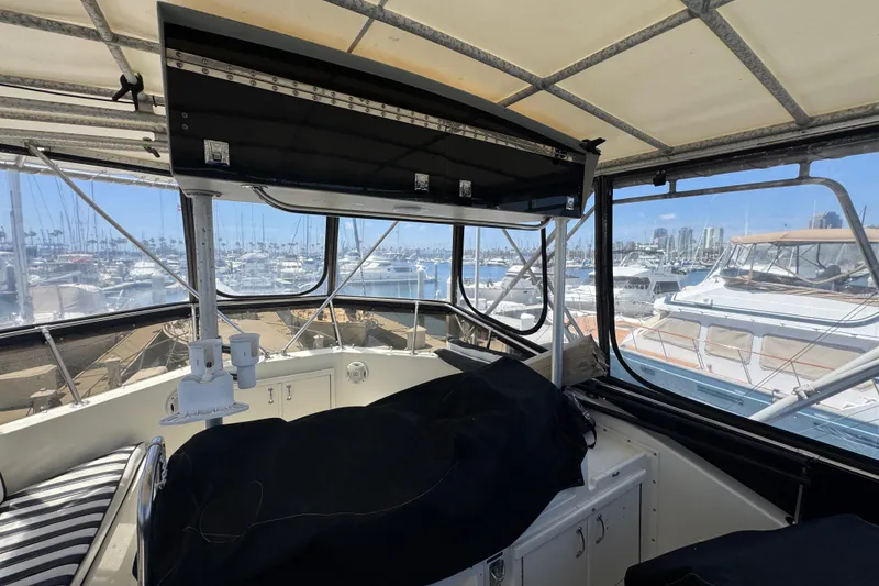 Slide: The Image of Interior view of 1985 Hatteras 45 Convertible yacht at marina, showcasing helm and seating area. - 13