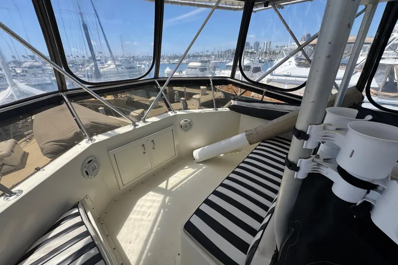 Slide: The Image of Interior view of 1985 Hatteras 45 Convertible yacht with striped seating and marina backdrop. - 14