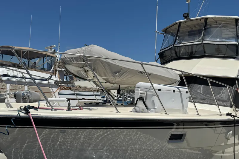 Slide: The Image of 1985 Hatteras 45 Convertible yacht docked, featuring covered equipment and clear blue sky. - 2