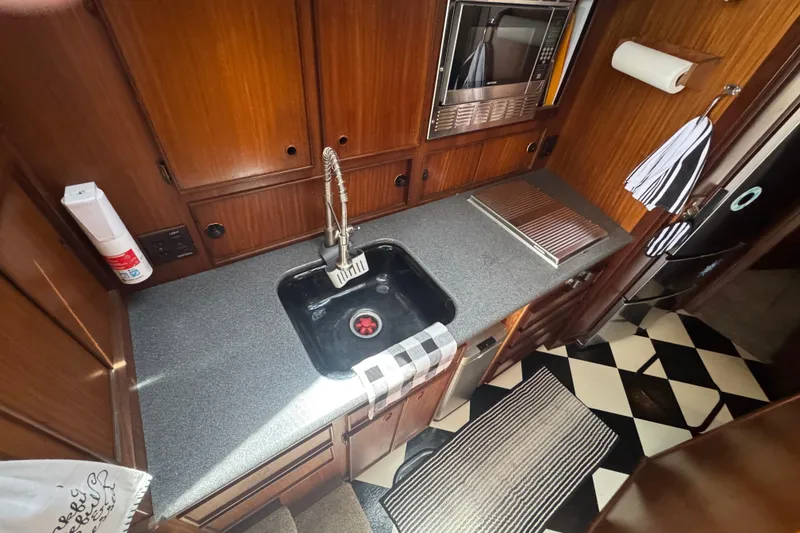 Slide: The Image of Galley kitchen in 1985 Hatteras 45 Convertible yacht with wood cabinetry and checkered floor. - 32