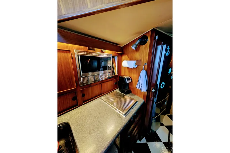 Slide: The Image of 1985 Hatteras 45 Convertible yacht kitchen with microwave, coffee maker, and wooden cabinetry. - 34