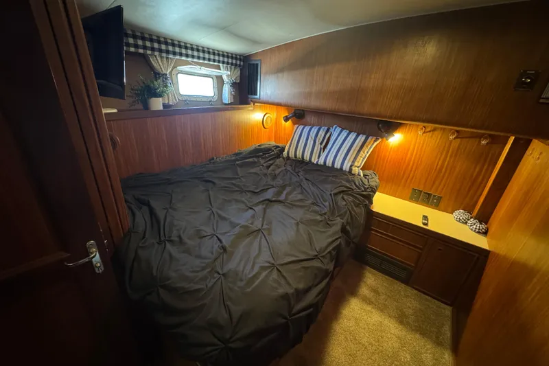 Slide: The Image of Cozy cabin interior of 1985 Hatteras 45 Convertible yacht with bed and window. - 45