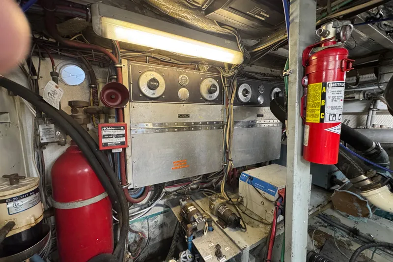 Slide: The Image of Engine room of a 1985 Hatteras 45 Convertible yacht with control panels and fire extinguishers. - 68