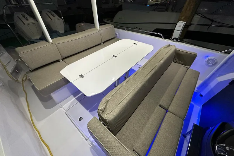 Slide: The Image of 2024 Axopar 37 Sun-Top boat interior with cushioned seating and a white table. - 18