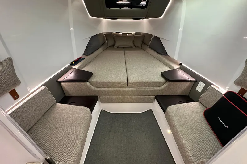 Slide: The Image of 2024 Axopar 37 Sun-Top cabin interior with modern seating and cozy bedding. - 9