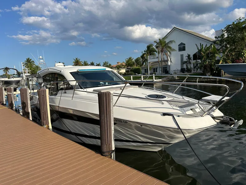 Slide: The Image of 2020 Four Winns Vista 355 Coupe docked by waterfront homes under a partly cloudy sky. - 2