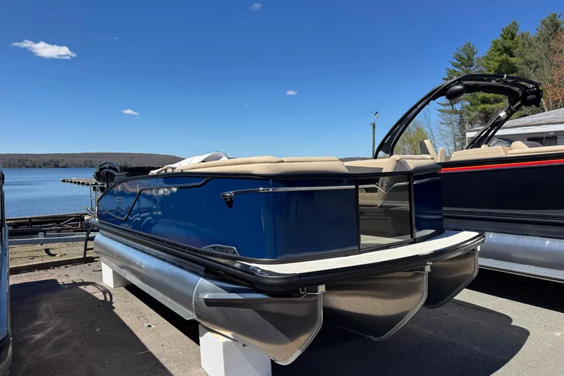 Slide: The Image of 2026 Harris Sunliner 210 pontoon boat docked by a serene lake under a clear blue sky. - 11