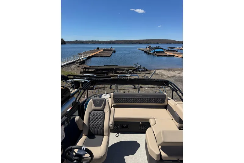 Slide: The Image of 2026 Harris Sunliner 210 pontoon boat docked by a serene lake under a clear blue sky. - 20