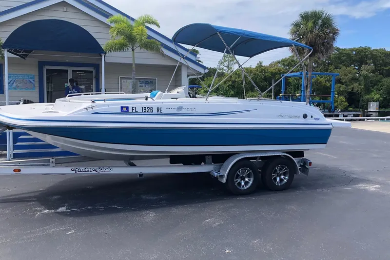 The Image of 2014 Hurricane SunDeck Sport 201 IO boat on trailer, parked outside a building. - 0