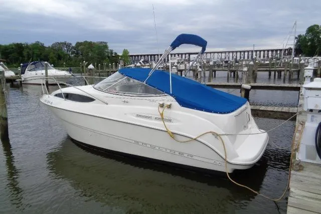 The Image of 2000 Bayliner 2455 Ciera Sunbridge boat docked with blue canopy in marina. - 0