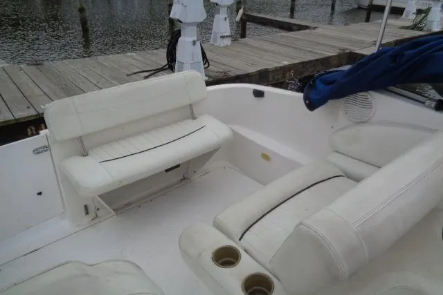Slide: The Image of 2000 Bayliner 2455 Ciera Sunbridge interior with white seating and cup holders at dock. - 20