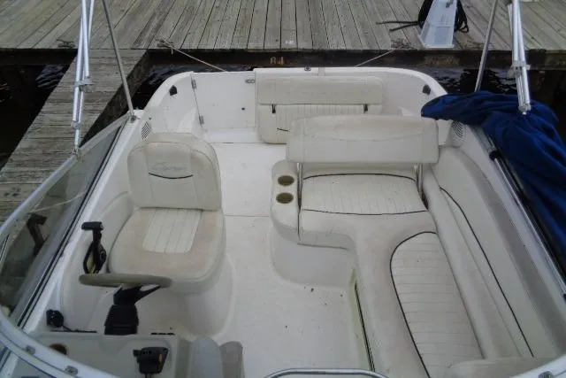 Slide: The Image of 2000 Bayliner 2455 Ciera Sunbridge boat interior with seating and steering wheel, docked at a wooden pier. - 22