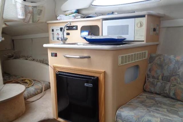 Slide: The Image of Interior of 2000 Bayliner 2455 Ciera Sunbridge with kitchenette, microwave, and seating area. - 25