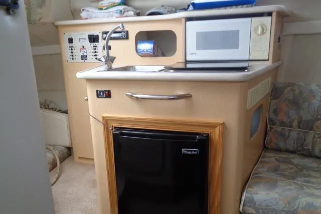 Slide: The Image of Compact kitchen area in a 2000 Bayliner 2455 Ciera Sunbridge boat, featuring a microwave and mini-fridge. - 27