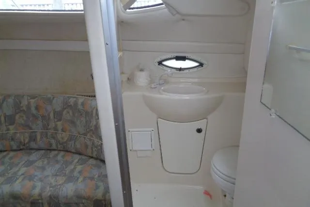 Slide: The Image of Interior of 2000 Bayliner 2455 Ciera Sunbridge, featuring compact bathroom and seating area. - 28