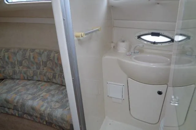 Slide: The Image of Interior of 2000 Bayliner 2455 Ciera Sunbridge, featuring a compact bathroom and seating area. - 29