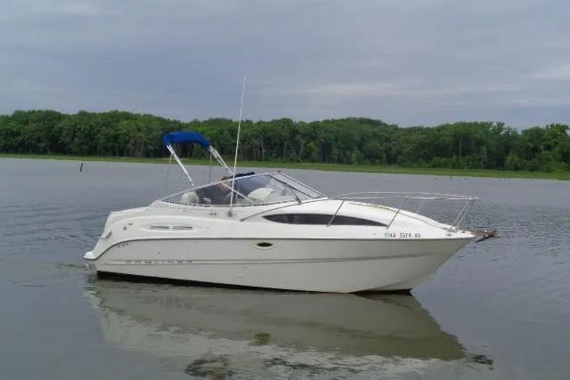 Slide: The Image of 2000 Bayliner 2455 Ciera Sunbridge boat on calm water with forested background. - 3