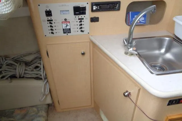 Slide: The Image of 2000 Bayliner 2455 Ciera Sunbridge interior with sink, control panel, and storage. - 34