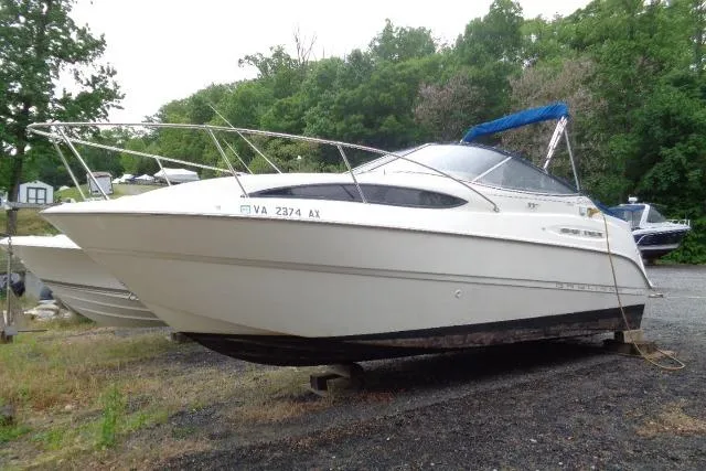 Slide: The Image of 2000 Bayliner 2455 Ciera Sunbridge boat on land, surrounded by trees. - 4