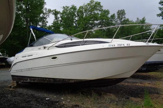 Slide: The Image of 2000 Bayliner 2455 Ciera Sunbridge boat on land, surrounded by trees. - 5