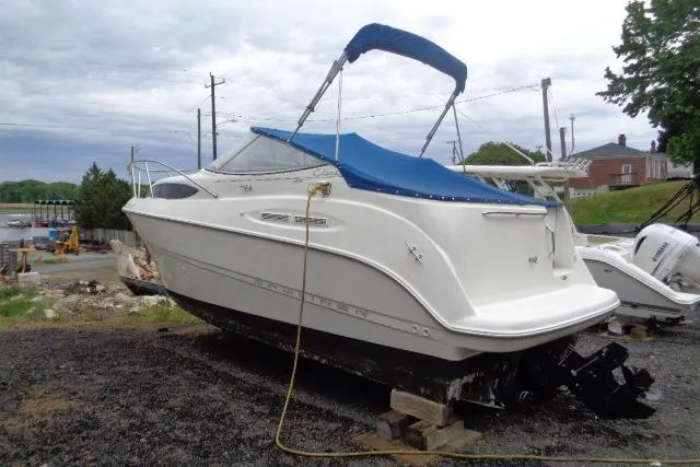 Slide: The Image of 2000 Bayliner 2455 Ciera Sunbridge boat with blue canopy, docked on land. - 6