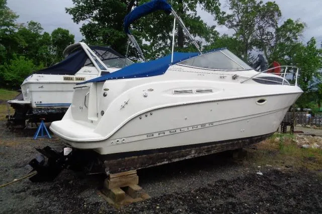 Slide: The Image of 2000 Bayliner 2455 Ciera Sunbridge boat on land with blue canopy. - 7