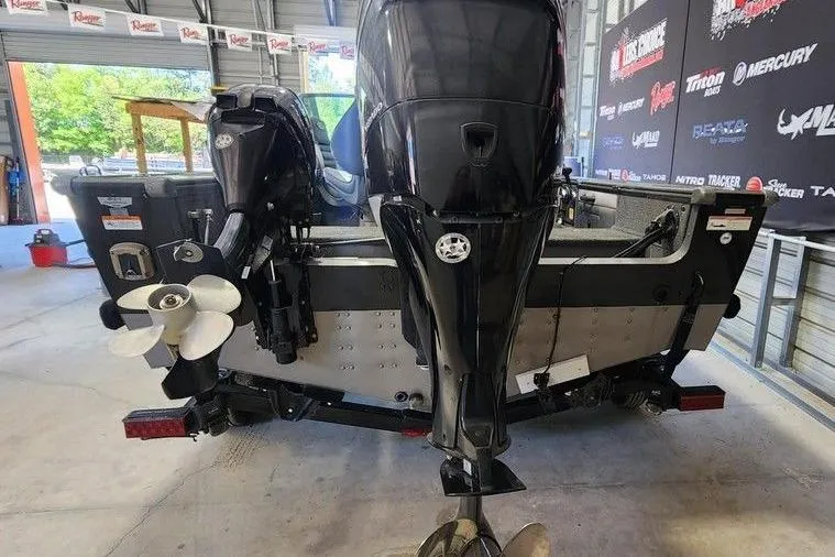 Slide: The Image of 2011 Lund 1975 Pro-V SE boat in a garage, showcasing its powerful outboard motor. - 2