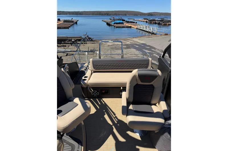 Slide: The Image of 2026 Harris Sunliner 230 Sport interior with beige seating, overlooking a serene lake and docks. - 10