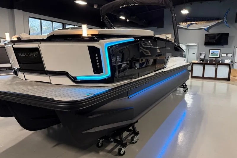 Slide: The Image of 2025 Balise Horizon 24 boat with sleek design and blue LED accents in showroom. - 25