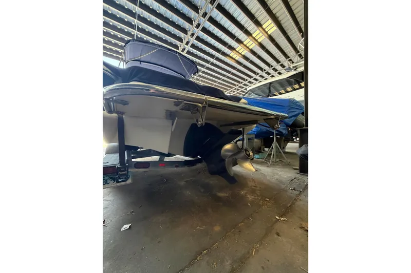 Slide: The Image of 2015 Cobalt 243 boat in storage, showcasing propeller and stern under a metal roof. - 54
