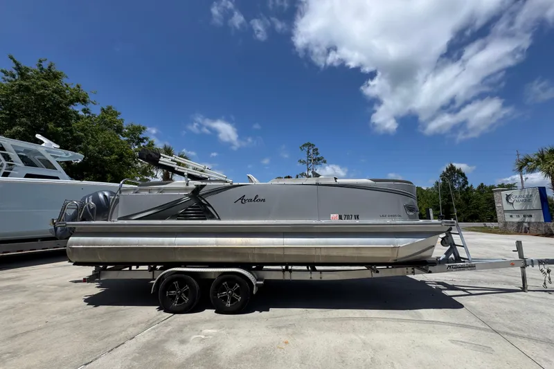 Slide: The Image of 2021 Avalon LSZ 2485 QL pontoon boat on trailer under clear blue sky. - 10