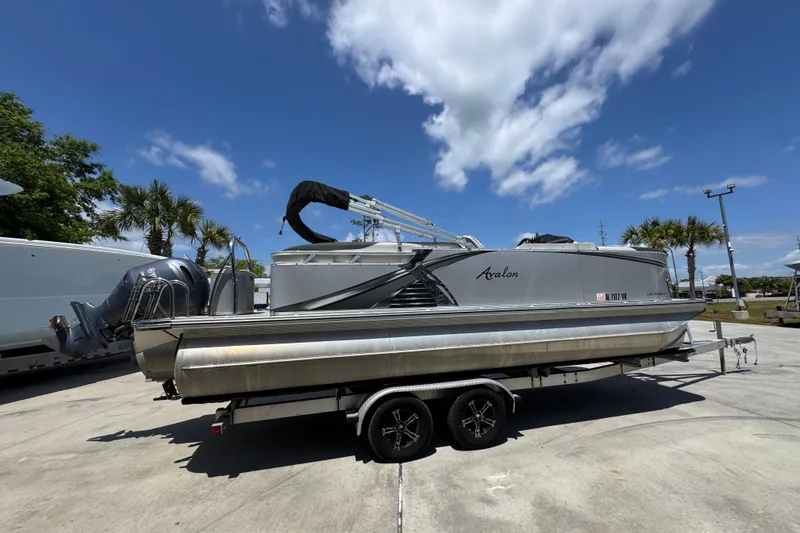 Slide: The Image of 2021 Avalon LSZ 2485 QL pontoon boat on trailer under blue sky. - 11