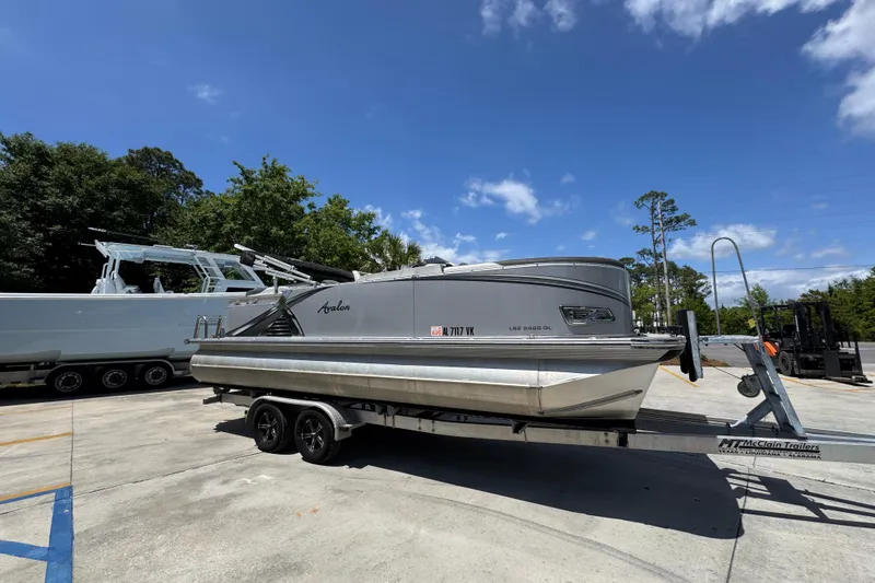Slide: The Image of 2021 Avalon LSZ 2485 QL pontoon boat on trailer under clear blue sky. - 9