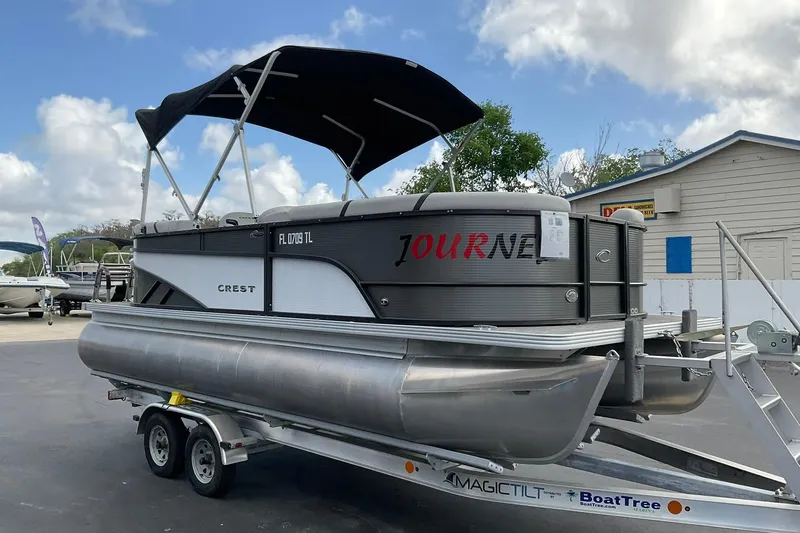Slide: The Image of 2023 Crest Classic LX 200 SLC pontoon boat on trailer, under a cloudy sky. - 3