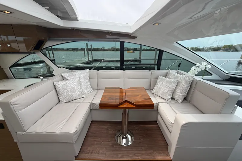 Slide: The Image of Luxurious seating area on a 2018 Cruisers Yachts 50 Cantius, featuring elegant cushions and a wooden table. - 15