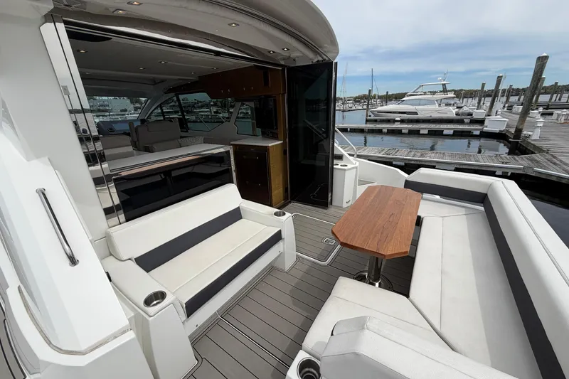 Slide: The Image of 2018 Cruisers Yachts 50 Cantius with elegant seating and wooden table at marina. - 3