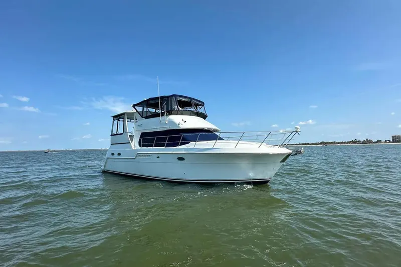 The Image of 2000 Carver 406 Motor Yacht cruising on open water under clear blue skies. - 1