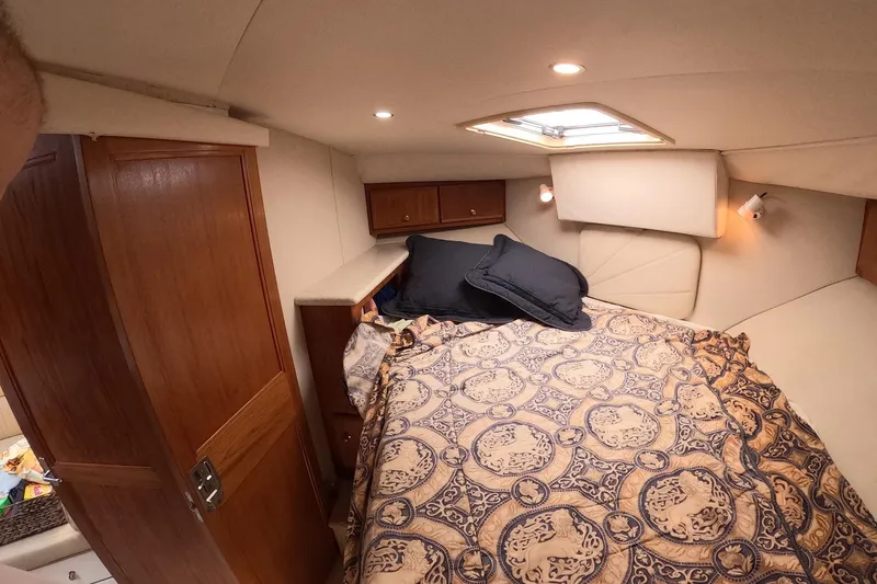 Slide: The Image of Cozy bedroom interior of 2000 Carver 406 Motor Yacht with patterned bedding and wooden cabinetry. - 4