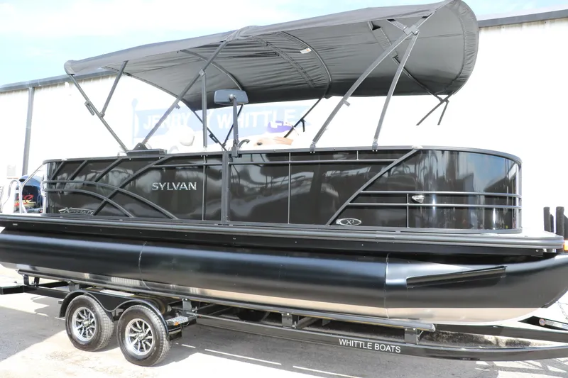 Slide: The Image of 2025 Sylvan Mirage X3 pontoon boat on trailer with canopy, sleek black design. - 6