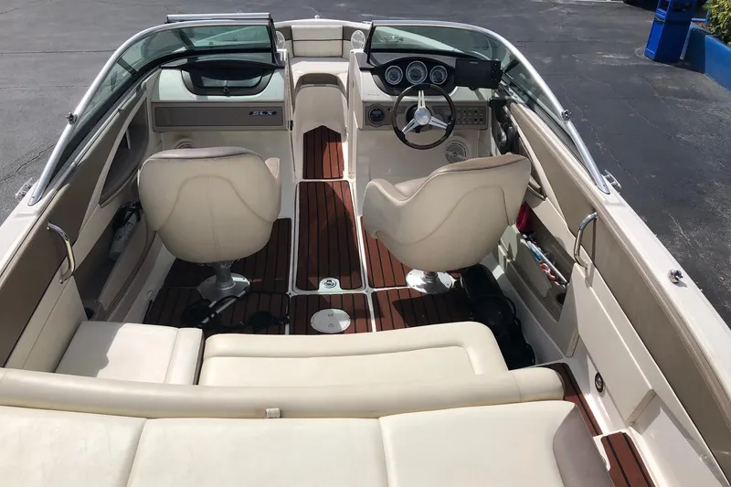 Slide: The Image of Interior view of a 2012 Sea Ray 210 SLX boat with beige seating and wooden flooring. - 10