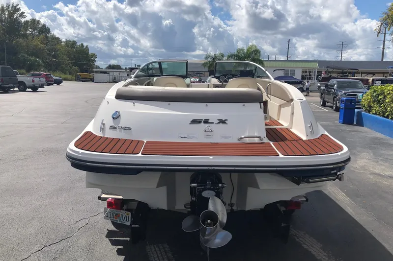 Slide: The Image of 2012 Sea Ray 210 SLX boat, rear view, parked outdoors under cloudy sky. - 3
