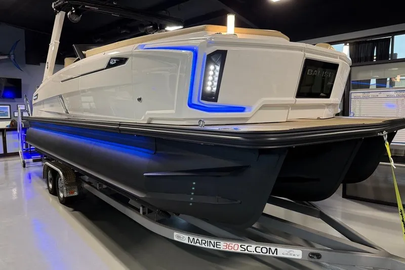 The Image of 2025 Balise Helix 26 L boat on trailer, illuminated with blue LED lights in showroom. - 1