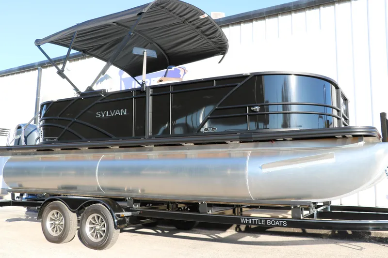 Slide: The Image of 2025 Sylvan Mirage X1 pontoon boat on trailer, featuring sleek black design and canopy. - 8