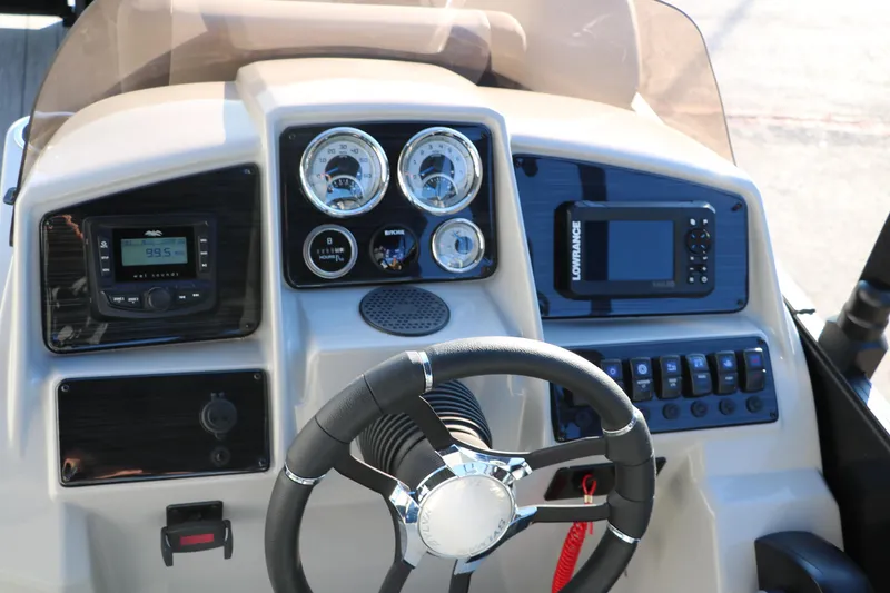 Slide: The Image of 2025 Sylvan Mirage X1 boat dashboard with steering wheel and electronic controls. - 26